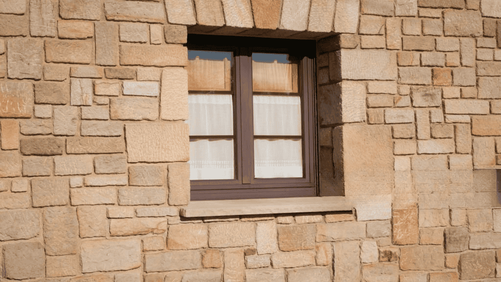 Stone masonry exterior wall with a small window framed in natural stone