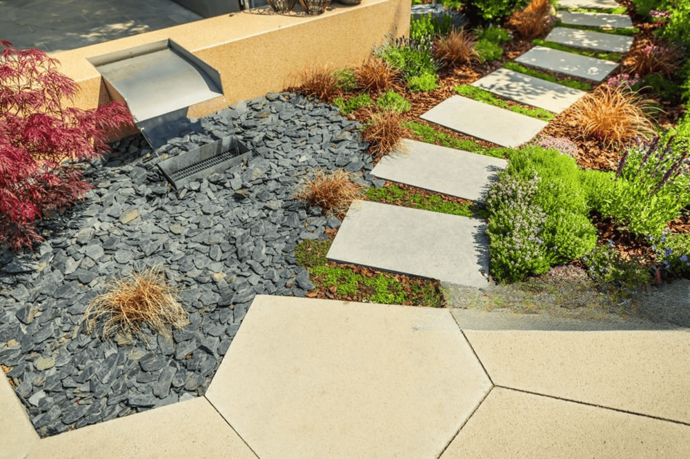 Modern outdoor landscaping with natural stone stepping stones, gravel ground cover, and low-maintenance garden design