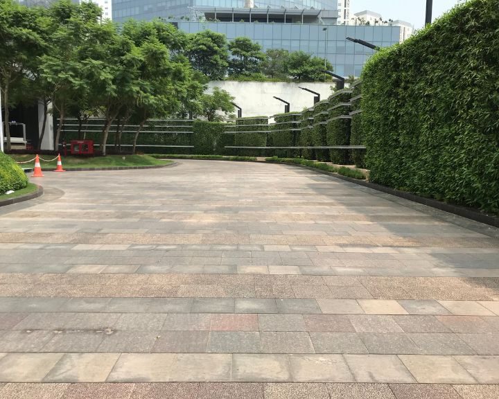 Commercial driveway paved with natural stone blocks, featuring curved layout and landscaped green walls