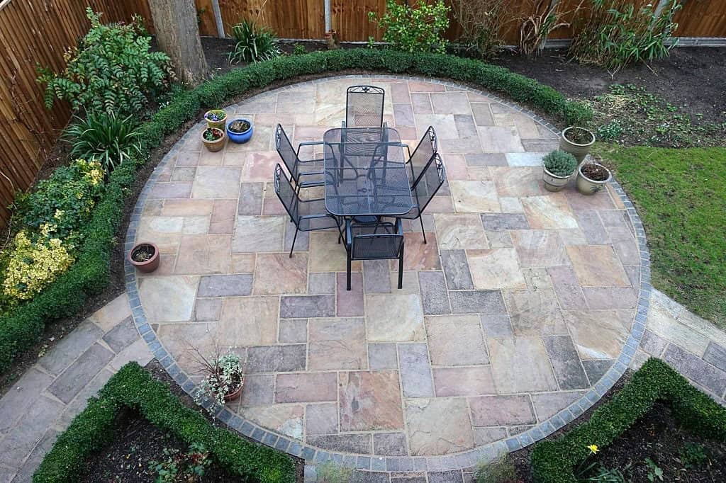 Beautiful circular patio designed with natural stone paving and garden seating area