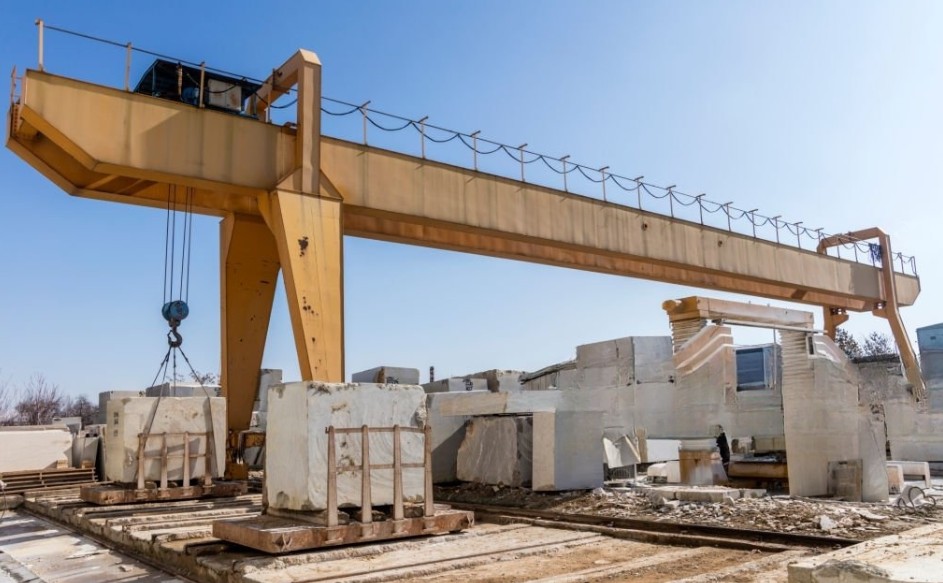 Natural stone manufacturing facility handling large stone blocks with industrial crane